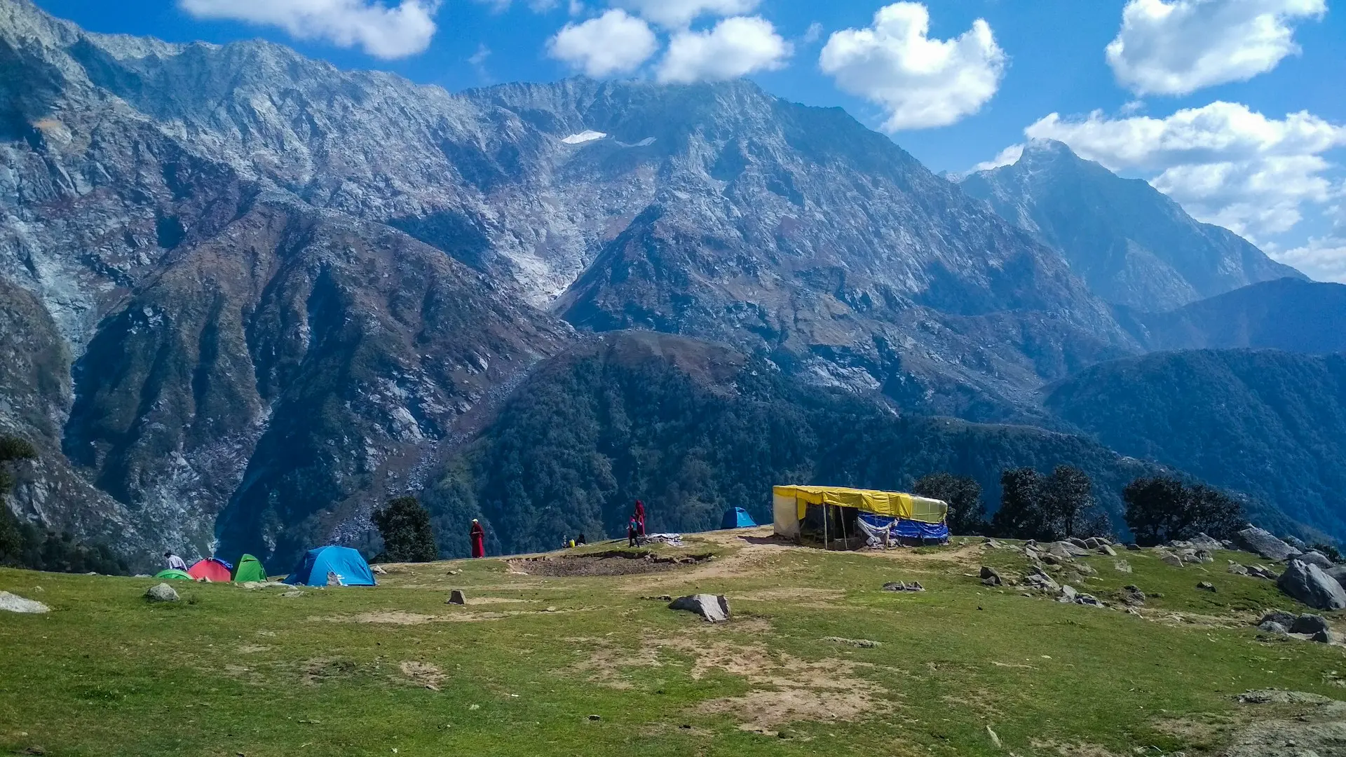 blue tent on green grass field near mountain during daytime